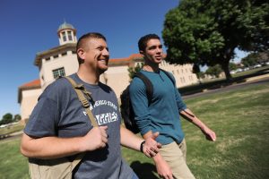 Two students walking in front of a building on campus.