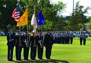 ROTC members standing with flags in the grass.